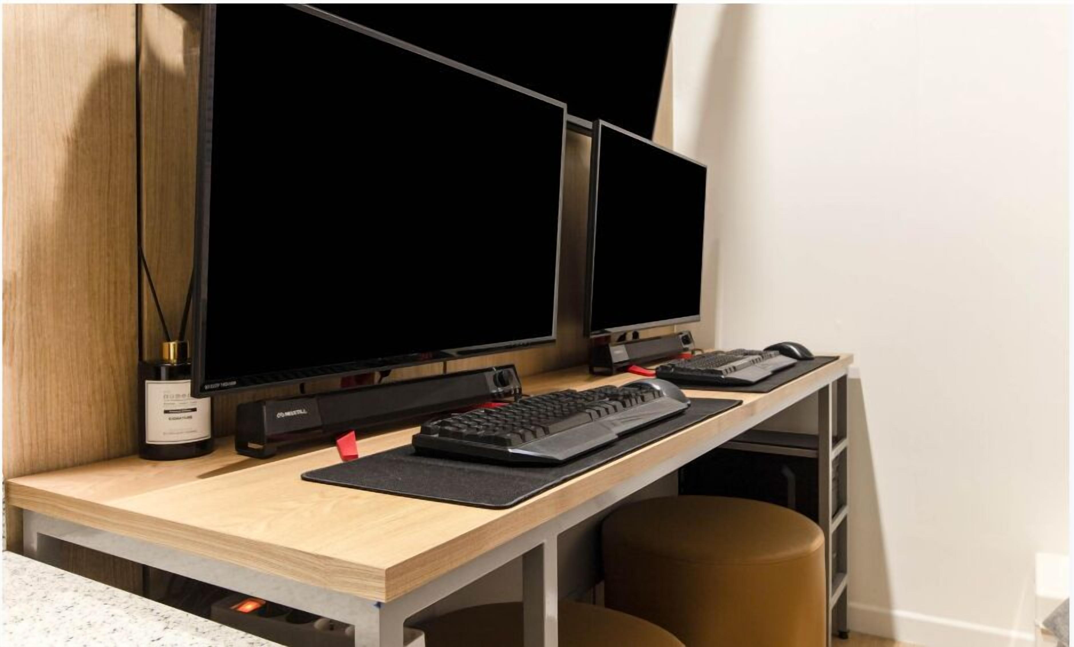 A workspace with two monitors, a keyboard, and a mouse on a wooden desk.