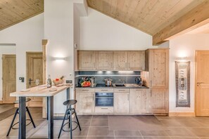 A modern kitchen with wooden cabinets, a central island, and a dining area with a table and stools.