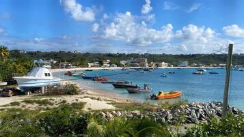Enjoy the serene coastal marina with boats docked and a picturesque beach.