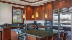 Une cuisine moderne avec des meubles en bois, des appareils en acier inoxydable et un grand îlot central doté de sièges.