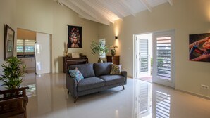 Un espacio habitable amplio con un sofá gris, un piano y un ventanal con persianas.