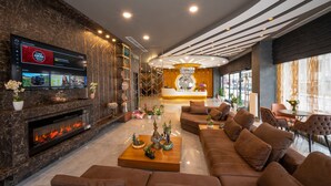 A modern lobby with a fireplace, comfortable seating, a reception desk, and a large TV screen. - Seyithan Palace Hotel  (Istanbul)