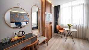 A modern hotel room with a round mirror, a wooden partition, a small table with a vase of flowers, and a seating area with a chair. - Seyithan Palace Hotel  (Istanbul)