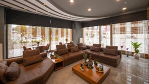 A modern living room with a sectional sofa, a coffee table, and large windows with blinds. - Seyithan Palace Hotel  (Istanbul)