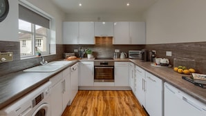 A modern kitchen with white cabinets, a wooden countertop, and a built-in oven. - Captivating 3-bed Apartment by Gleneagles (Auchterarder)