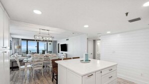 A modern kitchen with white cabinetry, a central island, and a dining area with a chandelier.