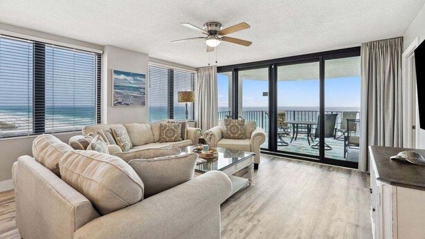 A spacious living room with a large sofa set, a coffee table, and a ceiling fan.