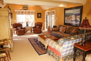 A cozy living room with a checkered sofa, two leather armchairs, a wooden coffee table, and a patterned rug.