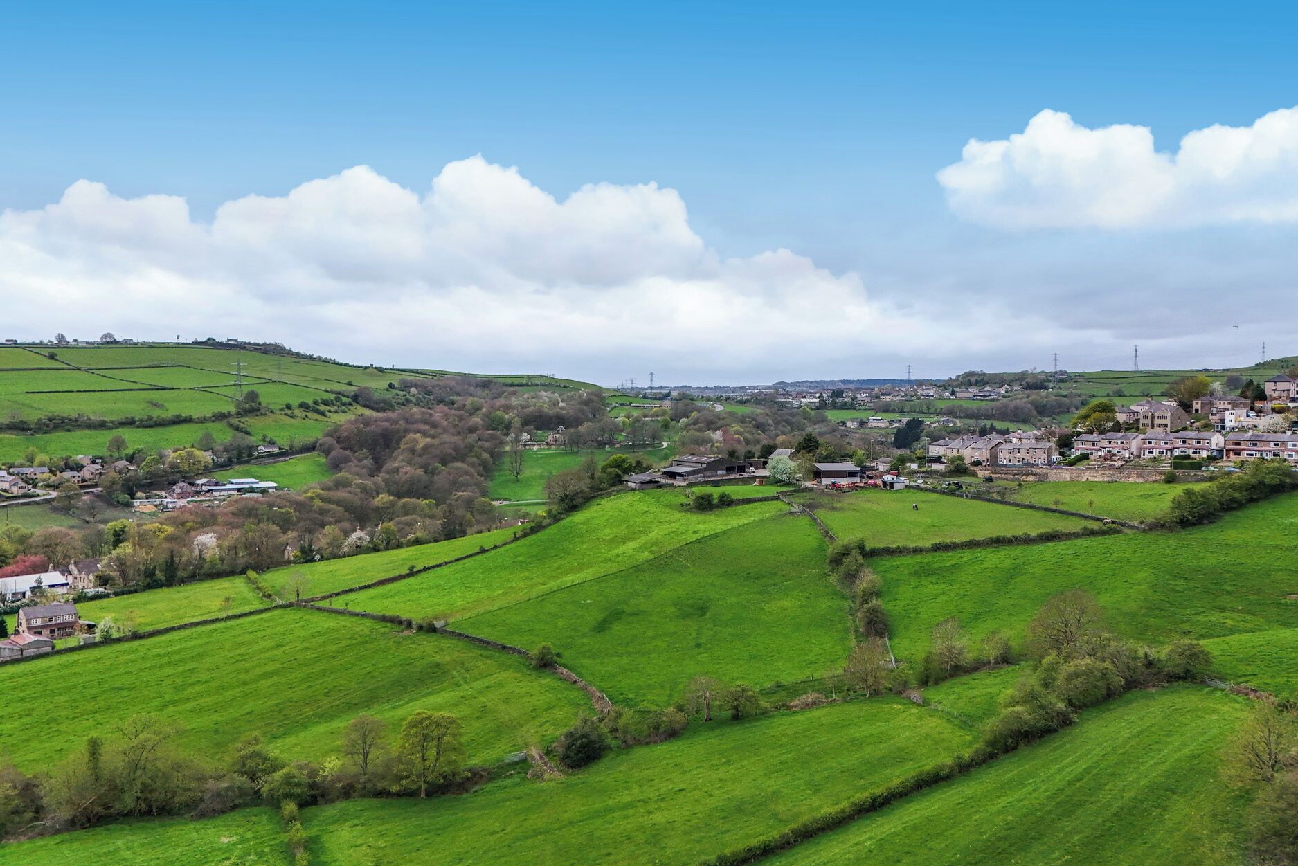 A rural landscape with fields, stone walls, and a small village.