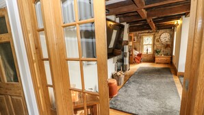 A wooden interior with a stone wall, a clock, and a rug leading to a cozy seating area. - Belvedere Farm (Halifax)