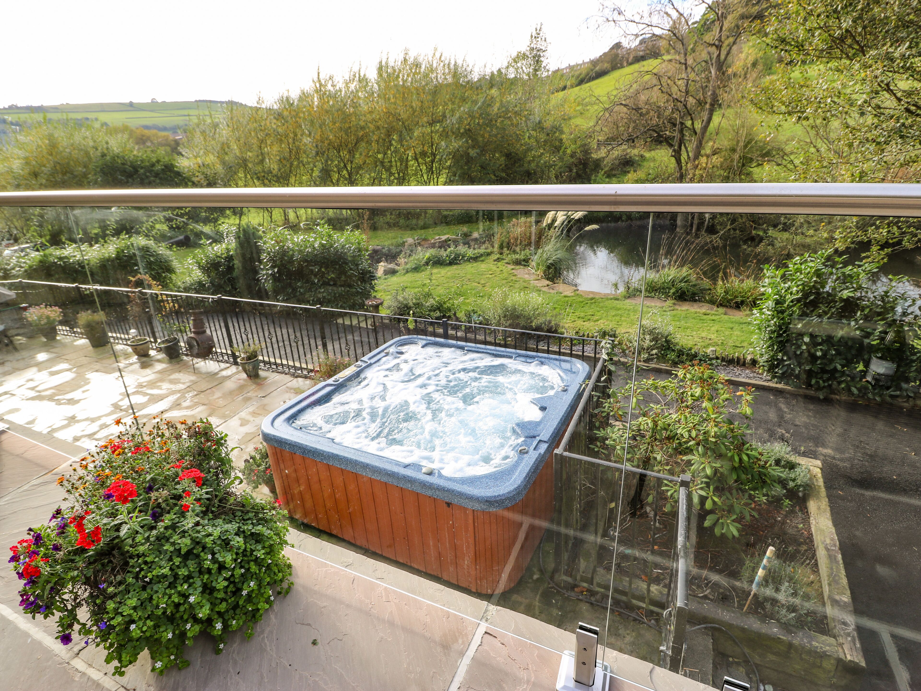 A hot tub on a balcony with a view of a river and greenery.