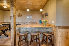 A wooden bar area with stools, a bar counter, and a clock on the wall.