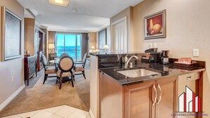 A modern kitchen with a large island, a dining area with a view, and a living space with a large window overlooking the ocean. - MGM Signature 1BR Sphere/F1 Balcony w full kitchen (Las Vegas)