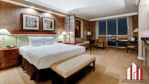 A hotel room with a large bed, a bench, a desk, and a view of the city. - Floor-to-Ceiling Jacuzzi Studio | The Signature (Las Vegas)