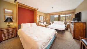 Habitación de hotel con dos camas, un escritorio, una silla, un televisor y vista al exterior.