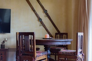 Een eetgedeelte met een houten tafel en stoelen, een gehangen zwaard en een televisie aan de muur.