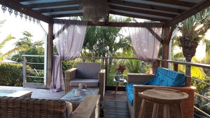 An outdoor patio with wicker furniture, a small table, and a decorative vase.