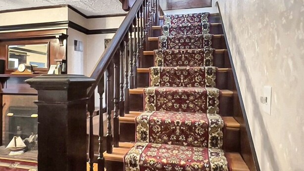 Una escalera con alfombra estampada y peldaños de madera.