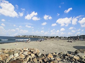 A beach with rocky foreground, a clear sky, and distant buildings. - Kurtz Cottage - Wonderful home minutes away from the Goldenrod and York Beach (York)
