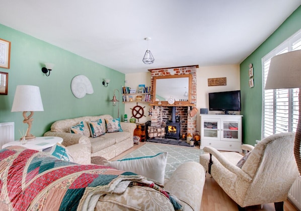 Cozy living room with a comfortable sofa set, armchair, and brick fireplace, perfect for relaxing with a good book.