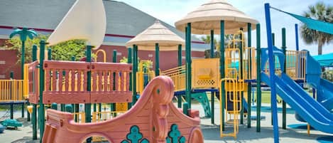 A playground with a pirate ship play structure, a slide, and a climbing area.