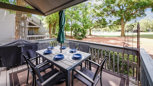 An outdoor patio with a covered table set for four, surrounded by chairs, and a covered grill. - Spacious Pup Friendly Villa w/ Golf Course Views (Hilton Head Island)