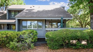 A two-story house with a covered porch, a small front yard, and a gravel driveway. - Spacious Pup Friendly Villa w/ Golf Course Views (Hilton Head Island)