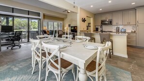 A dining area with a white table set for six, surrounded by wicker chairs. A ceiling fan with four blades is above the table. - Spacious Pup Friendly Villa w/ Golf Course Views (Hilton Head Island)