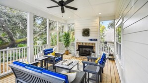 A covered outdoor deck with a fireplace, seating area, and large windows. - Convenient Location to Beach & Downtown (Hilton Head Island)