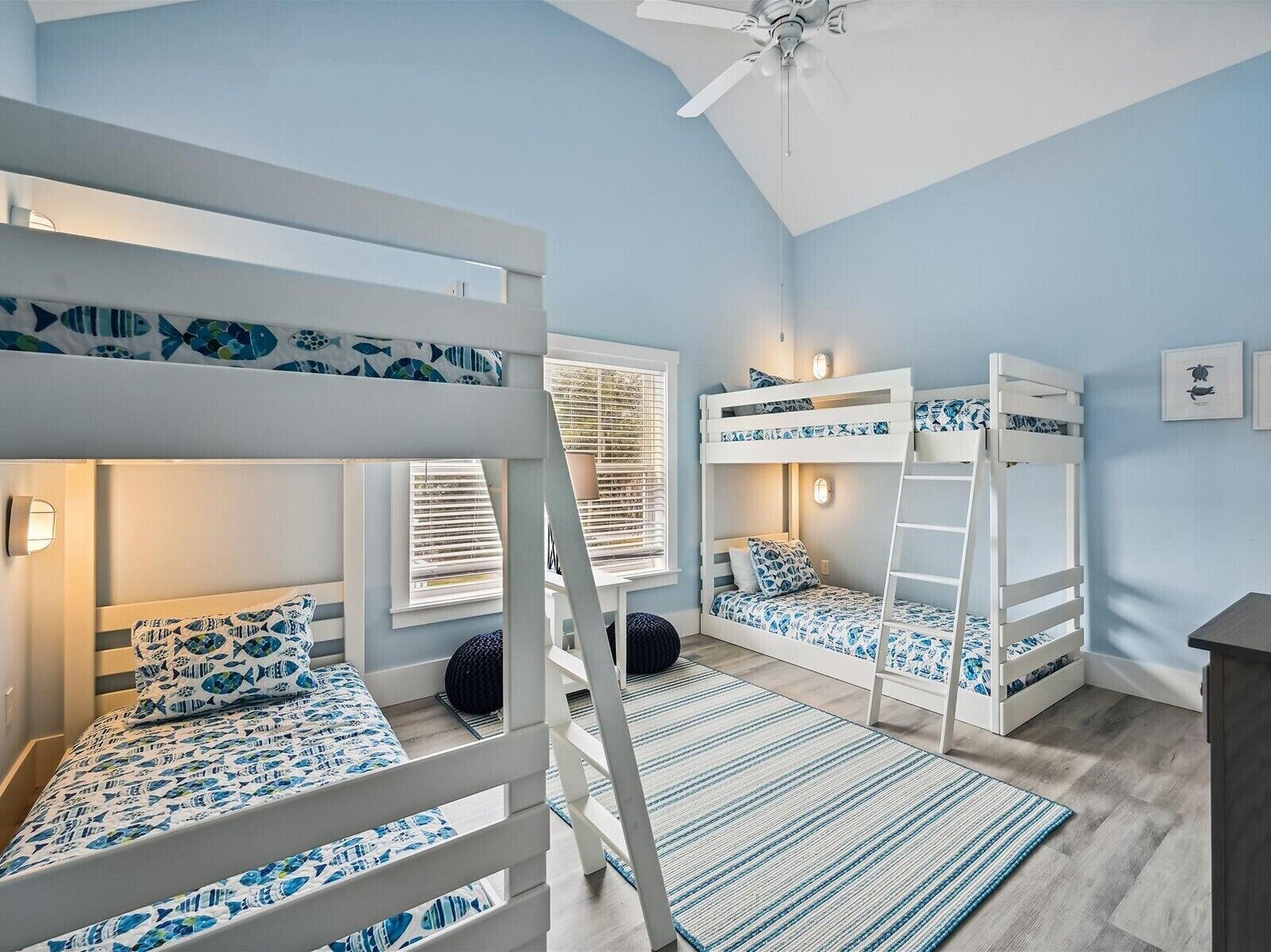 A room with bunk beds, a ceiling fan, and a window with blinds.