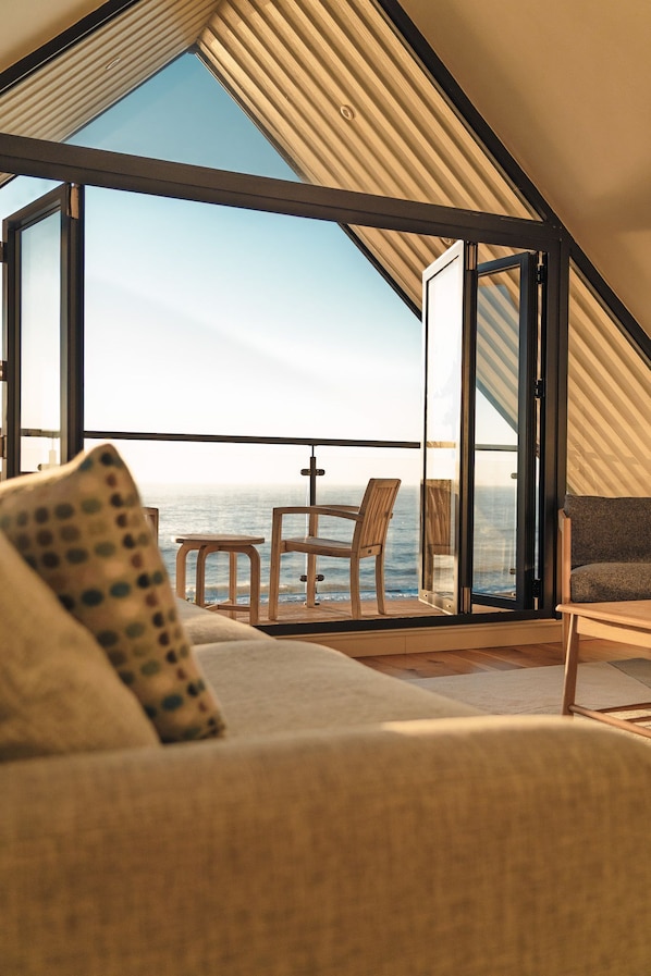 Ein Zimmer mit einer großen Schiebeglasdoor, die auf einen Balkon mit Meerblick führt.
