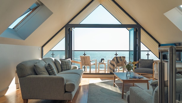 Un dormitorio tipo loft moderno con un tragaluz grande, un sofá, una mesa de centro y vistas al mar.