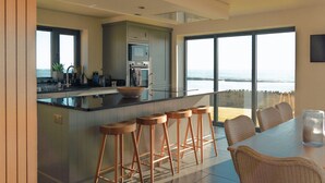 Una cocina moderna con una isla grande, taburetes de bar y una mesa de comedor con sillas.