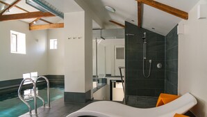 A modern indoor swimming pool with a lounge area, a shower, and a view of the adjacent room. - Oughtershaw Hall -  a large propertie that sleeps 16 guests  in 8 bedrooms (Skipton)