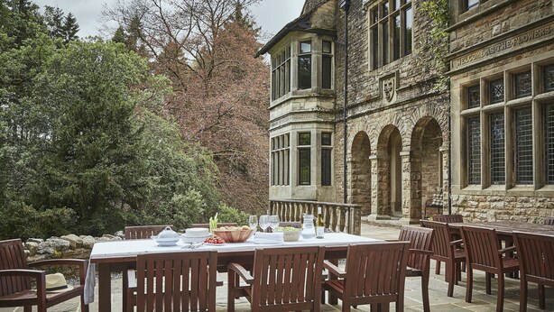 An outdoor dining area with a stone building in the background. - Oughtershaw Hall -  a large propertie that sleeps 16 guests  in 8 bedrooms (Skipton)