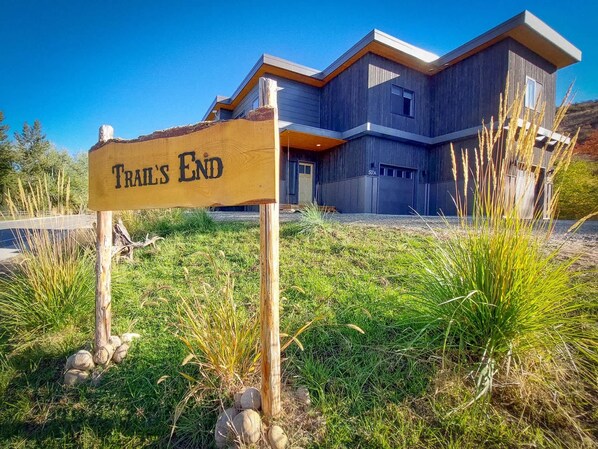 A modern building with a 'Trail's End' sign, surrounded by grass and rocks.