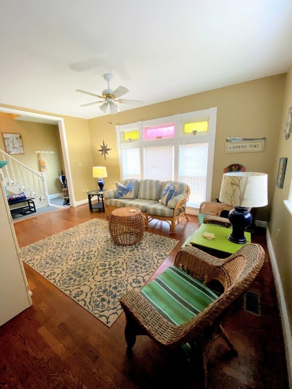 A living room with a sofa, a coffee table, a wicker chair, a floor lamp, and a star decoration on the wall. - Welcome to K9 Beach House (South Haven)