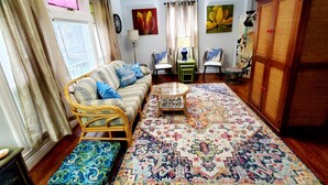Een woonkamer met een bank, stoelen, een salontafel en een vloerkleed met dessin.