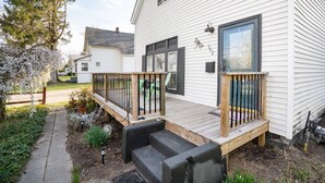 Een wit huis met een houten terras en zwarte leuningen.