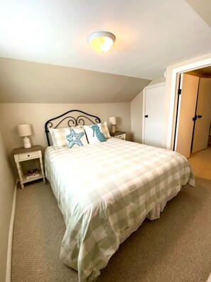 A bedroom with a bed, bedside tables, a nightstand, and a door. - Steps Away (South Haven)