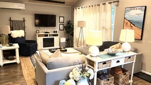 Ein Wohnzimmer mit Deckenventilator, Fernseher, Sofa, Couchtisch und Lampe.