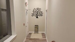 A hallway with a brown leather chair, a tree mural on the wall, and a wooden floor. - Unique geometric shapes this Villa (Jeffersonville)