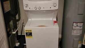 A compact washer and dryer unit with a control panel, located in a small utility room with wooden flooring. - Unique geometric shapes this Villa (Jeffersonville)