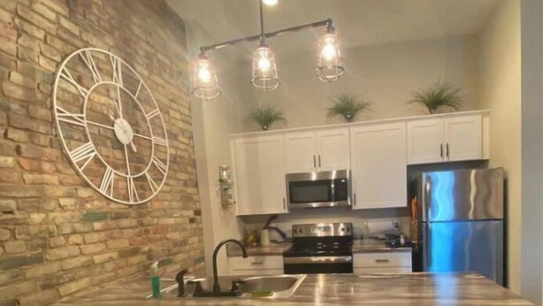 A modern kitchen with a large island, stainless steel appliances, and a decorative clock on the wall. - Unique geometric shapes this Villa (Jeffersonville)