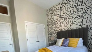 A bedroom with a bed, a bedside table, a wall with abstract art, and a door. - Unique geometric shapes this Villa (Jeffersonville)