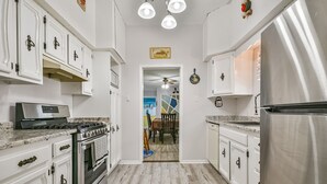 Una cocina con muebles blancos, un refrigerador de acero inoxidable, un horno empotrado y una estufa a gas.