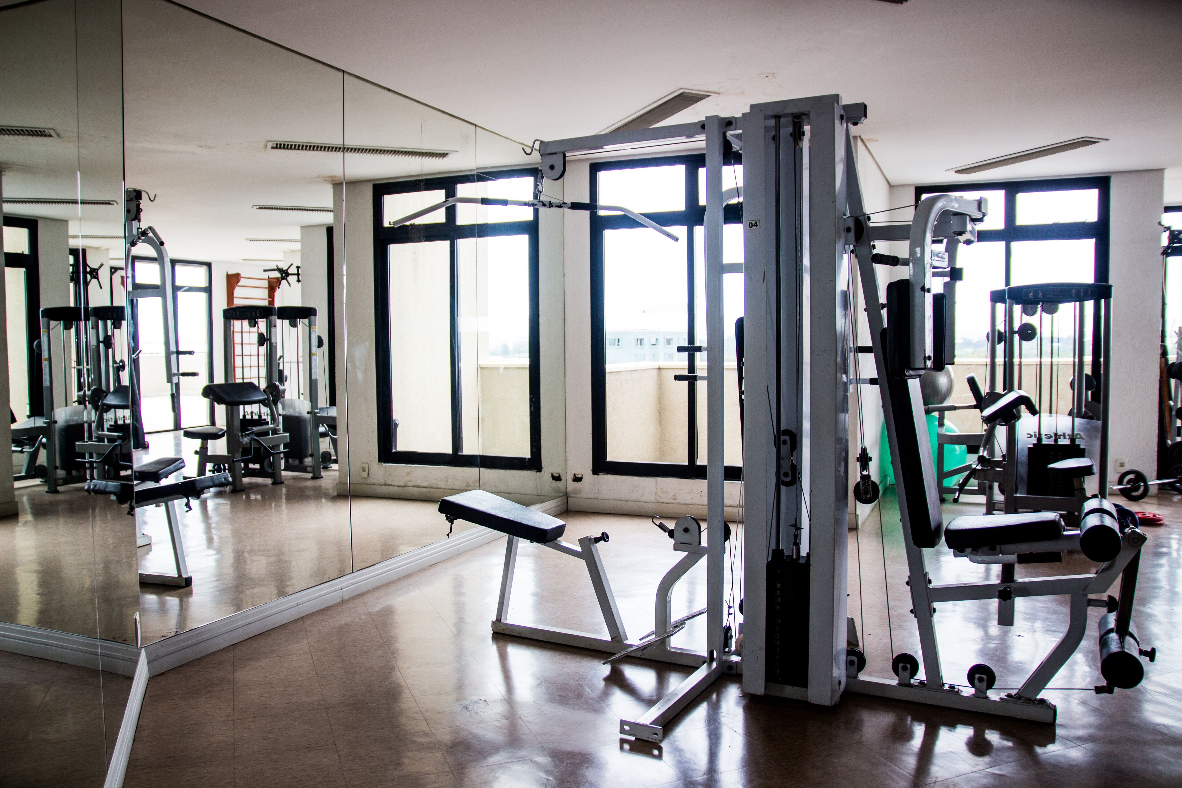 Une salle de sport équipée de matériel d’exercice, dotée de grandes fenêtres et d’un miroir.
