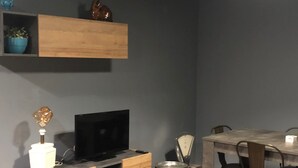 Una sala moderna con un mueble de televisión de madera, una mesa de comedor con sillas y una balanza de cocina.