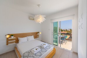 Un dormitorio moderno con una cama grande, mesitas de noche, una lámpara en el techo y vistas al balcón exterior.