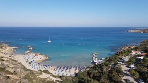 Una zona costera con playa, barcos y coches aparcados.